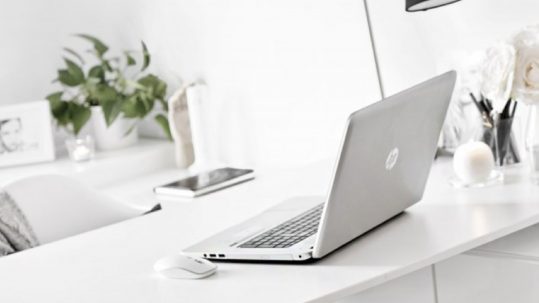 Image of a office desk with a MacBook computer and lamp