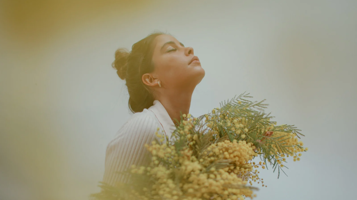 Woman holding flowers, representing self-compassion and nurturing mental wellbeing in a psychology clinic setting