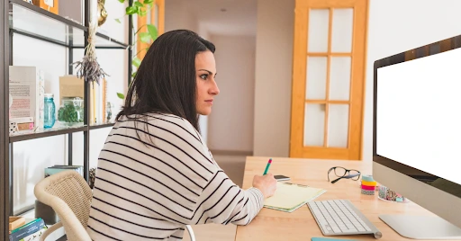 Positive Wellbeing Psychology Melbourne | Obsessive-Compulsive Disorder vs. Being Detail-Oriented: Where's the Line? Woman sitting at a computer desk writing down notes while studying or working.